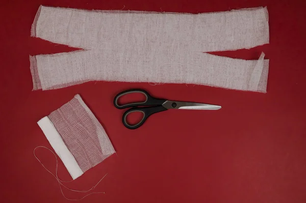 Kendiniz yapın tıbbi maske düz yatıyordu. Gazlı bez, makas ve iğne kullanarak kendi maskeni kendin dik. Enfeksiyon koruma konsepti. Coronavirus Covid-19 eczanelerde tıbbi maske sıkıntısına neden oluyor..