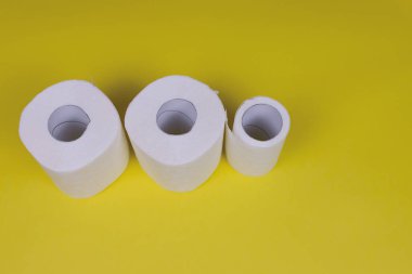 Sarı arka planda üç rulo tuvalet kağıdı. Coronavirus Covid-19 karantinasından dolayı tuvalet kağıdı krizi. Yakın çekim alan derinliği