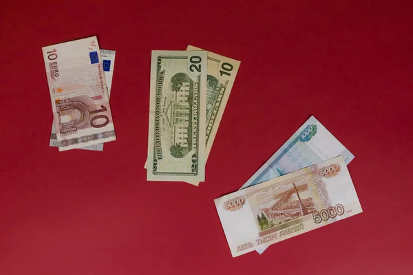 Banknotes Euro, US Dollars and Russian Rubles on red background. Ruble collapse. Fall of the ruble. Dollar rate growth. Money and finance. Euro rate growth.
