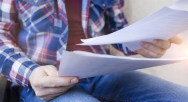 Kareli gömlek giyen adam belgelerle çalışıyor, kağıtlar evde. Uzaktan kumanda. Online eğitim. Karantinaya alın. Kendini soyutlama. Serbest meslek hayatı. Pankart