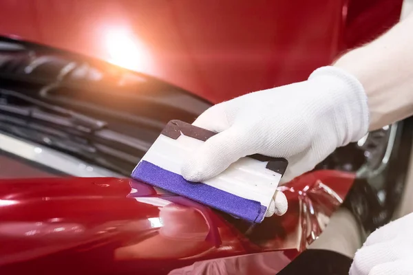 Özel bir aletle özel bir araba ve vinil film yapıştırma uzmanı. Araba bakımı. Araç bakımı. Yakın çekim alan derinliği.