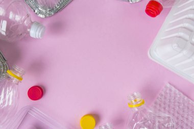 Şişeler ve konteynırlar pembe arka planda fotokopi alanı ile düzdü. Plastik konsepti durdur. Plastik ve alüminyum atık. Çöp geri dönüşümü. Plastiğe hayır de. Çöp ayıklama. Ekolojik kirlilik.