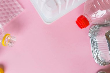 Şişeler ve konteynırlar pembe arka planda fotokopi alanı ile düzdü. Plastik konsepti durdur. Plastik ve alüminyum atık. Çöp geri dönüşümü. Plastiğe hayır de. Çöp ayıklama. Ekolojik kirlilik.