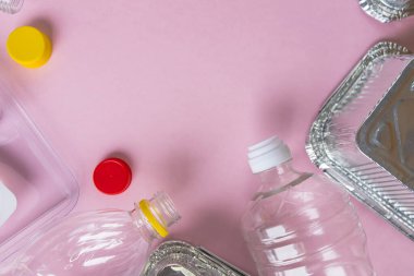 Şişeler ve konteynırlar pembe arka planda fotokopi alanı ile düzdü. Plastik konsepti durdur. Plastik ve alüminyum atık. Çöp geri dönüşümü. Plastiğe hayır de. Çöp ayıklama. Ekolojik kirlilik.