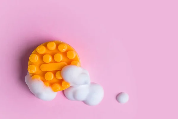 Cilt bakımı kozmetik. Köpüklü turuncu masaj sabunu pembe arka planda fotokopi alanı ile yatıyordu.. 