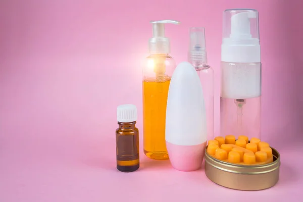 Skin care cosmetics set. Facial wash gel, massage soap, deodorant, essential oil in a bottle cosmetic spray. Front view on pink background with place for text.