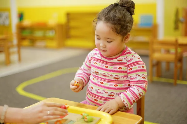 kazakh curly girl playing in kids development center