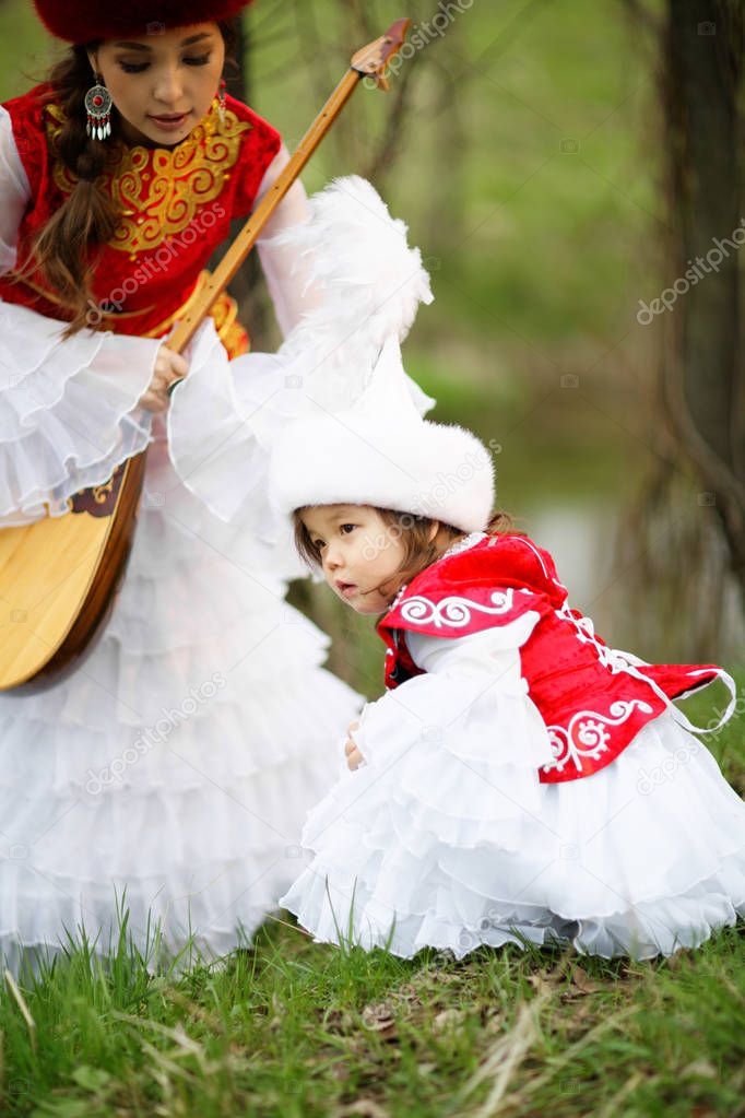 Kazakh people in national costumes. Woman and daughter in the park