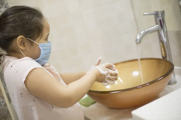 Pretty little asian kazakh girl in mask washing her hands. Person, Man, woman in mask.