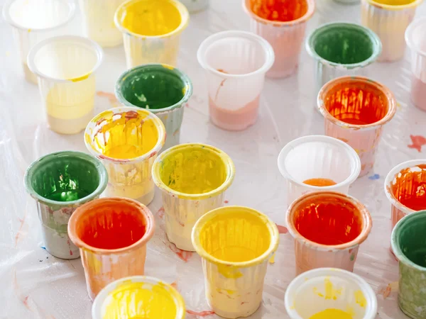 Tazza di plastica colorata su tavola Tavolozza colori pittura Immagini Stock Royalty Free