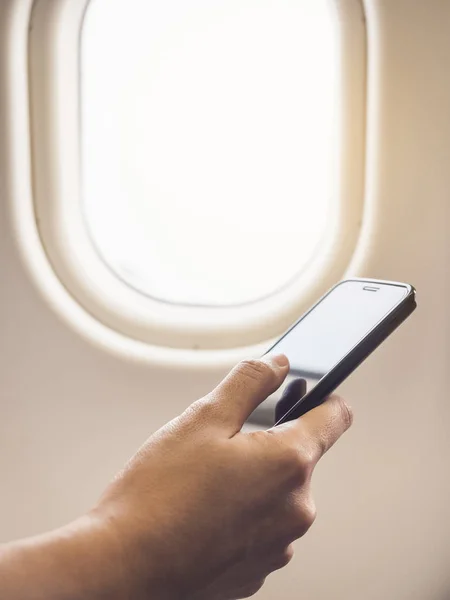 Akıllı telefon uçuş pencere kenarı gemide tutan el — Stok fotoğraf