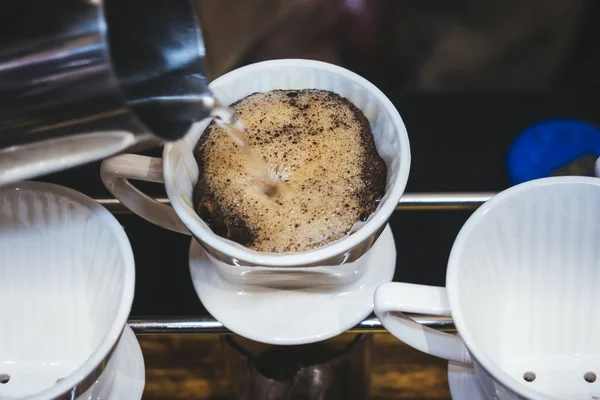 Handtropfkaffee, der heißes Wasser auf Kaffeesatz gießt — Stockfoto