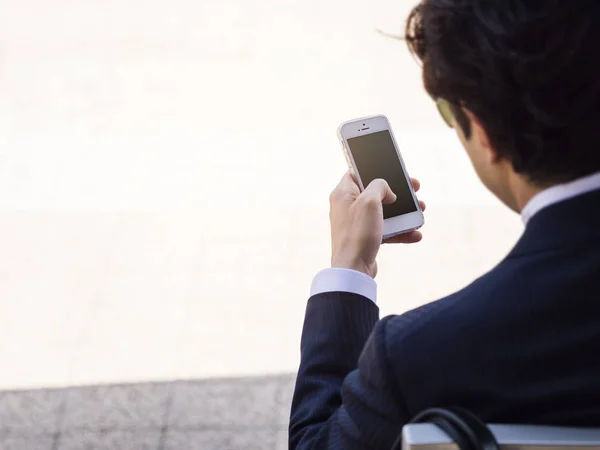 Бизнесмен держит в руках смартфон с пустым экраном — стоковое фото
