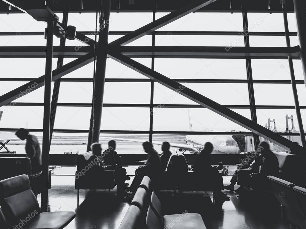 Passengers sit in airport terminal departure gate waiting area Silhouette people