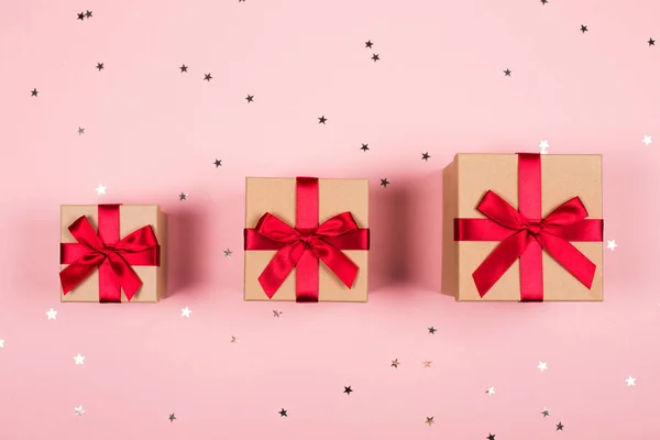 Τρία δώρα με κόκκινο φιόγκο στο ροζ — Φωτογραφία Αρχείου