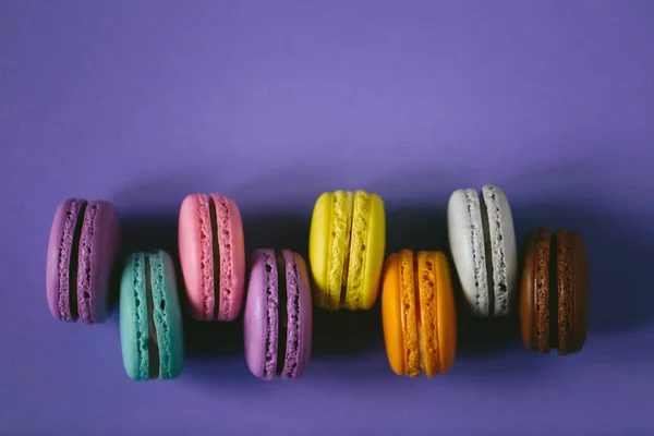 Macaroons multicoloridos em fundo violeta . — Fotografia de Stock