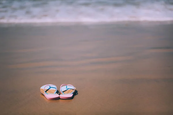 Pantoufles tendance sur la plage de sable . — Photo