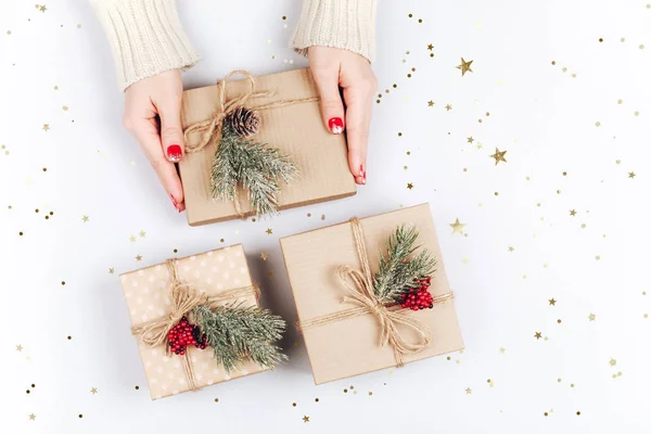 As mãos da mulher e três caixas de presente de Natal — Fotografia de Stock