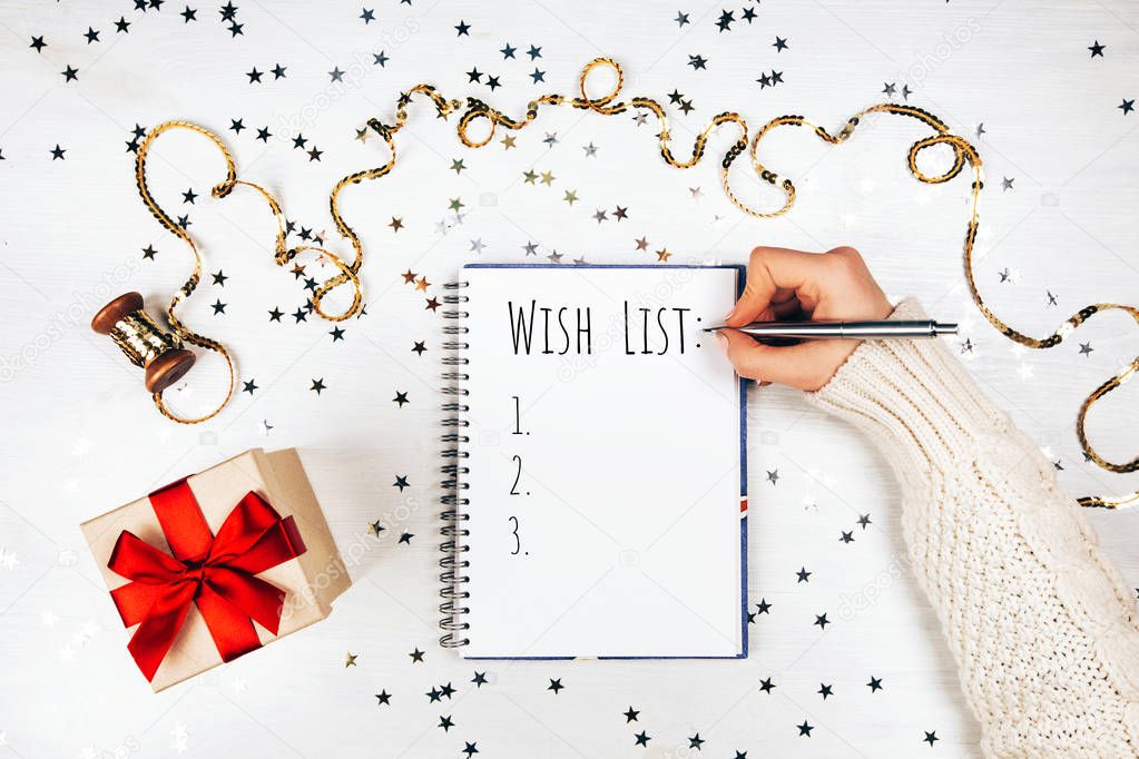 Holiday decorations and woman writing opened notebook on white rustic table, flat lay style. Christmas planning concept.