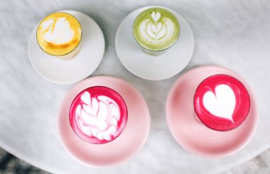 Trendy multicolored lattes. Beetroot, avocado and turmeric tastes with latte art and flower petals on foam. clipart