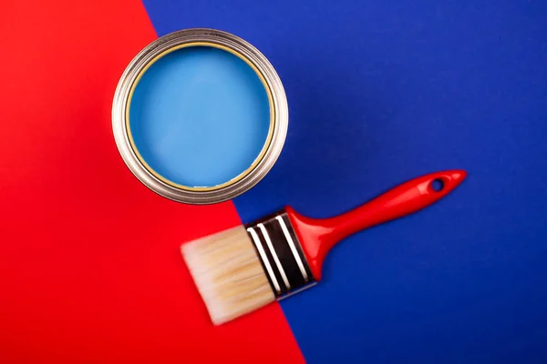 Cepillo en lata abierta de pintura azul sobre fondo azul y rojo . —  Fotos de Stock