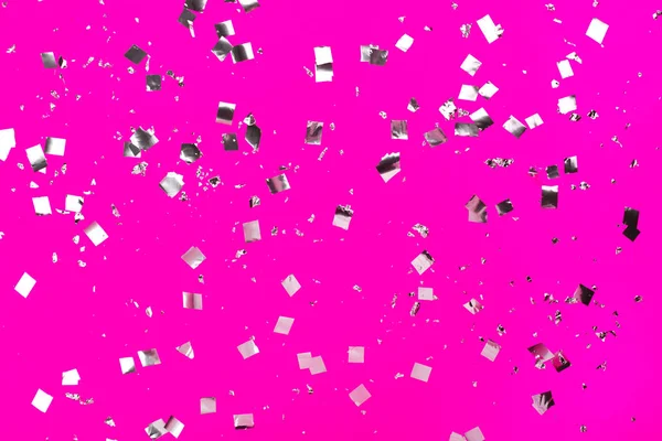 Падающие серебряные конфетти на розовом фоне . — стоковое фото