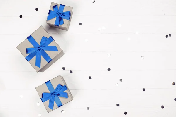Τρία κουτιά δώρο με μπλε φιόγκο σε ξύλινο φόντο. — Φωτογραφία Αρχείου