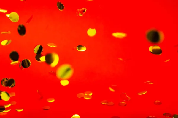 Guld faller konfetti på rött — Stockfoto