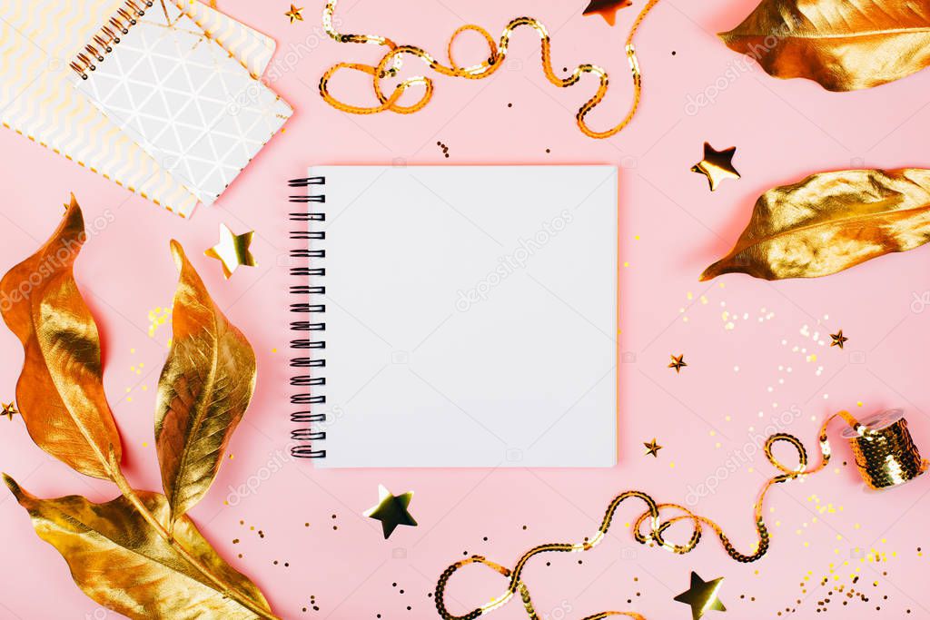 Note book on pink background with golden decorations.