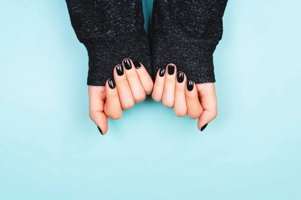 Hands with black manicure in long sleeve — Stock Photo, Image