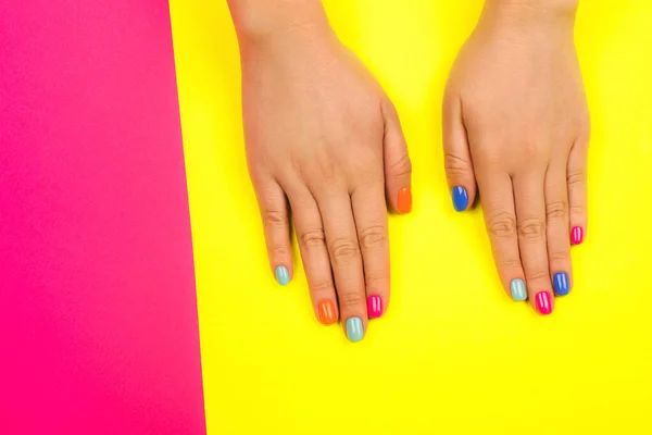 Manos femeninas con manicura perfecta en colores neón de moda sobre fondo brillante . — Foto de Stock