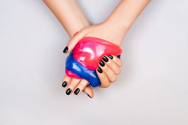 Mani con manicure nera tenendo melma — Foto Stock