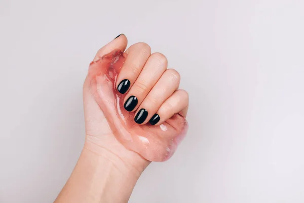 Black manicure holding slime