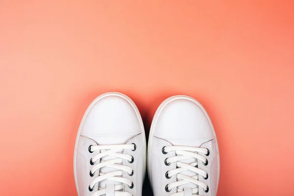 Toes of white trendy sneakers on bright orange background. — Stock Photo, Image