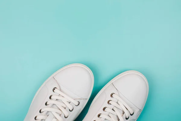 Toes of white trendy sneakers on turquoise background. — Stock Photo, Image