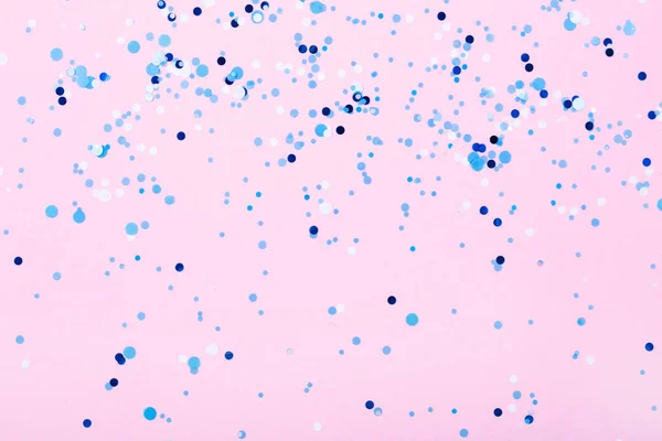 Spadające niebieskie konfetti na różowym tle. — Zdjęcie stockowe