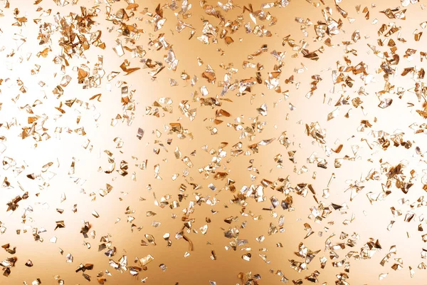 Golden falling confetti on metallic backdrop — Stock Photo, Image