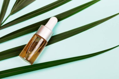 Bottle of essential oils or fluid collagen on blue background. Beuty concept. Flat lay style.