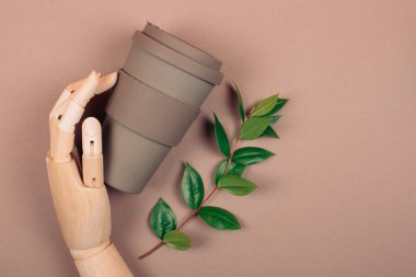 Tahta el tekrar kullanılabilir bir fincan kahve tutuyor. Plastiksiz ve sıfır atık yaşam kavramı