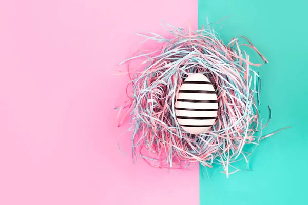 青とピンクのパステルの背景に装飾的な巣の中のグラフィック手描きのラインの卵 イースターのコンセプト — ストック写真