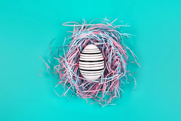 Mavi Pastel arka planda dekoratif yuvada çizgi yumurta el boyalı grafik. Paskalya konsepti.