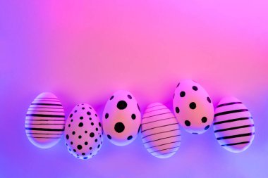 Proton Purple Neon ışıkta farklı grafik el boyalı yumurta. Paskalya konsepti. Üst görünüm.