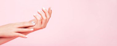 Kusursuz mavi ve pembe manikürlü yumuşak eller modayı takip eden pembe arka planda. Metin için yer.