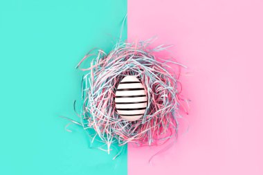 Pastel arka planda dekoratif yuvada elle boyanmış yumurta..