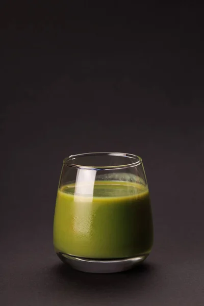 Green detox juice over black background.