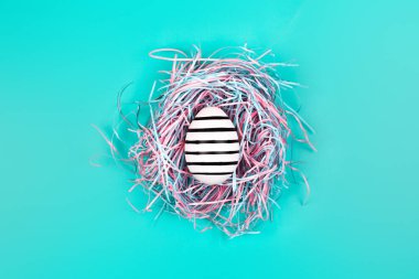 Mavi Pastel arka planda dekoratif yuvada çizgi yumurta el boyalı grafik. Paskalya konsepti.