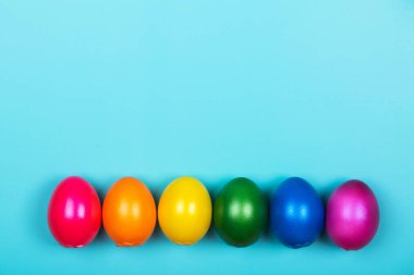 Mavi pastel arka planda neon renkli farklı renkte yumurtalar.
