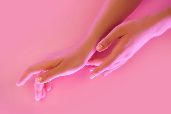 Mani delle donne con manicure perfetta in luce neon alla moda su sfondo rosa . — Foto Stock