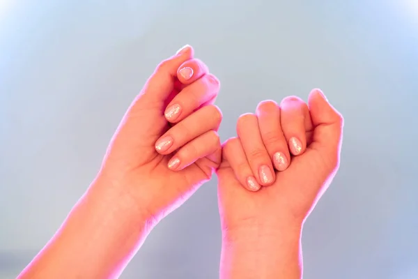 Kobiece dłonie z doskonałym manicure w modnym neonowym świetle na szarym tle. — Zdjęcie stockowe