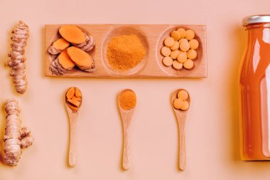 Farklı eyaletlerde zerdeçal: Şişe, hap, toz ve tahta tepside bitki, ahşap kasede kurumuş kök.